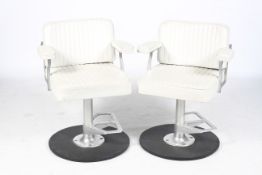 A pair of white vinyl hairdresser's beauty salon chairs.