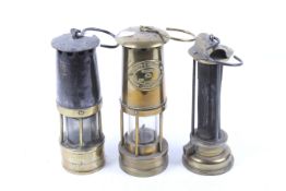 Three vintage miners lamps. Including an E Thomas & Williams Ltd brass example, No 30470, H25.