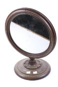 A 20th century oak toilet mirror. Of circular form, mounted on a shaped circular base, H45.