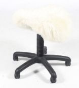 A contemporary sheep skin covered typist seat. No back rest.