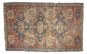 A red ground rug with blue central medallions. A blue stylized wave boarder. L212cm x W130cm.
