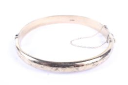 A vintage 9ct gold part foliate engraved hollow hinged bangle. Hallmarks for Birmingham 1965, 7.