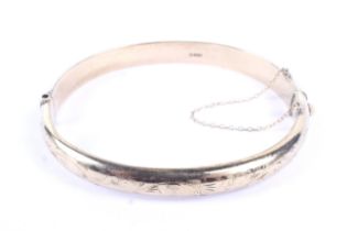 A vintage 9ct gold part foliate engraved hollow hinged bangle. Hallmarks for Birmingham 1965, 7.