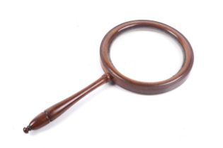 A mahogany framed magnifying 'picture' glass lens. With a turned handle, H38cm x Diameter 18.