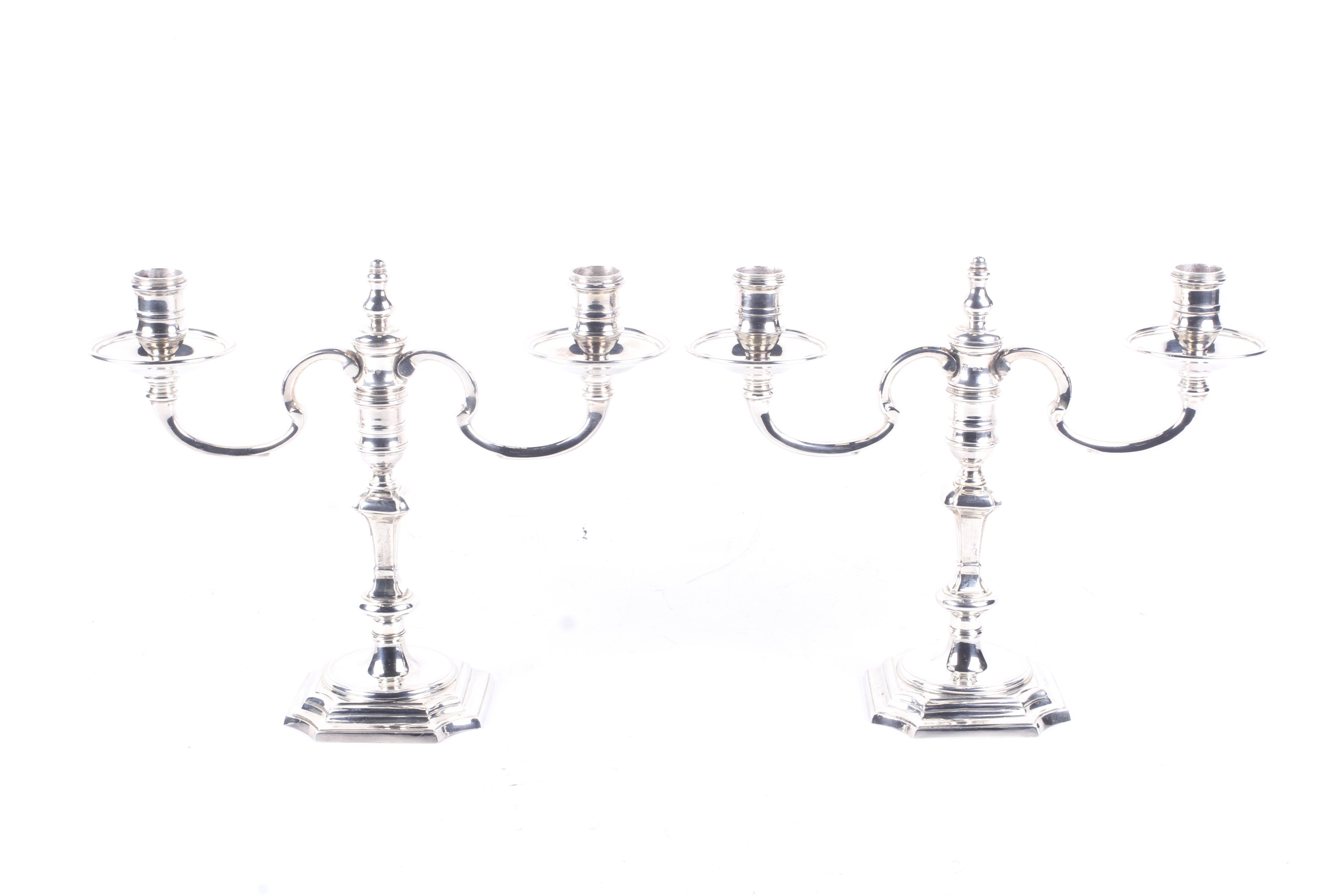 A pair of cast silver two-branch two-light candelabra in George I style.