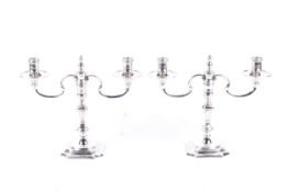 A pair of cast silver two-branch two-light candelabra in George I style.