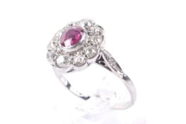 A mid 20th century platinum, ruby and diamond oval cluster ring.