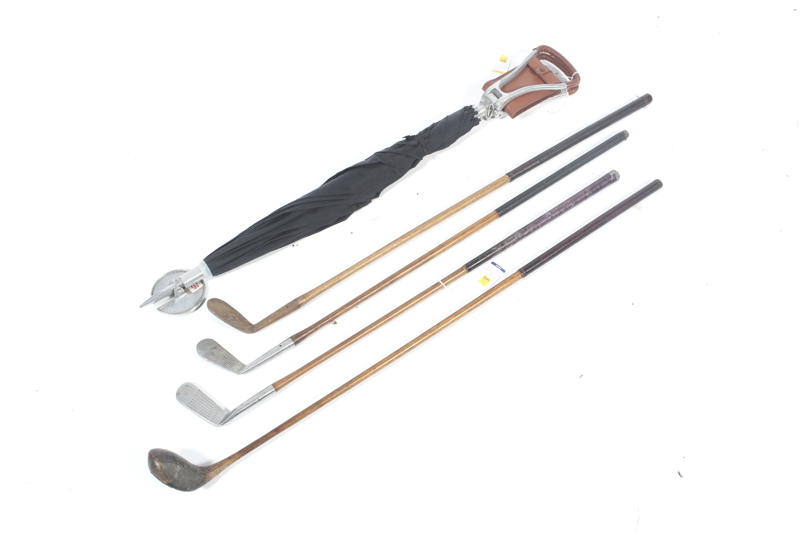 Four Hickory golf clubs and a shooting stick umbrella.