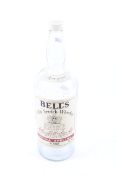A large empty glass bottle of Bell's Old Scotch Whisky.