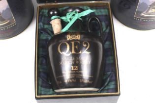 Two Bell's scotch whisky decanters and a bottle of QE2 single malt whisky.