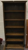 A tall dark stained oak bookcase of five shelves.