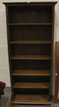 A tall dark stained oak bookcase of five shelves.