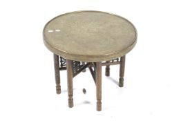 A Persian style chased brass tray top folding table. On a six-legged folding stand.