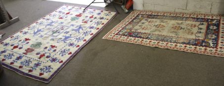 Two assorted cream, red and blue wool rugs. With stylized geometric floral patterns.