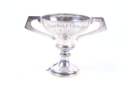 A silver small trophy cup with two angular handles.