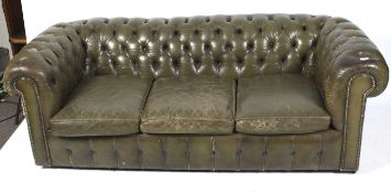A three seater green leather Chesterfield sofa. Button back, with scroll arms. Some wear.