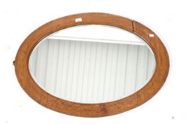 A vintage bevelled edge wall mirror. Of oval form, with an inlaid oak frame, 64.