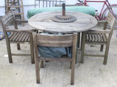 A Windsor Design Indonesian hardwood garden table and four chairs set with a parasol.