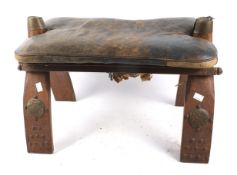 A vintage leather camel saddle style stool.