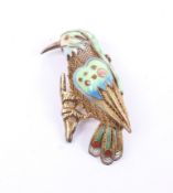 A filigree silver-gilt and polychrome enamel brooch in the form of an exotic bird on a branch.