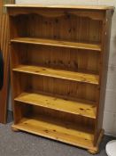 A contemporary pine bookcase. With serpentine upper apron over three shelves.