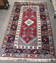 A Kirman Halicilik Persian style red ground wool rug.