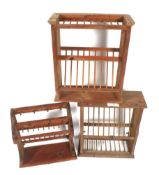 Three stained pine plate racks. Of various forms, all with racking and peg hooks.
