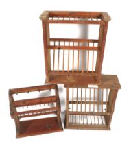 Three stained pine plate racks. Of various forms, all with racking and peg hooks.