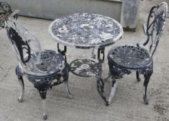 A cast metal garden table and two chairs set.