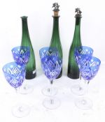 A set of six blue Bohemian glasses and three green bottles.