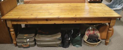 A large pine dining table. Of reclaimed wood, with a honey stain, on sturdy turned supports.