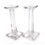 A pair of glass candlesticks. In a tinted grey colour, with a tapered stand and square base.