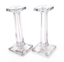 A pair of glass candlesticks. In a tinted grey colour, with a tapered stand and square base.
