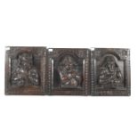 Three carved wooden figural panels.