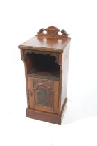 A Victorian carved mahogany bedside pot cupboard. With carved gallery and panel door.