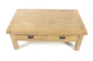 A contemporary blond oak coffee table. With two drawers to either side, raised on square supports.