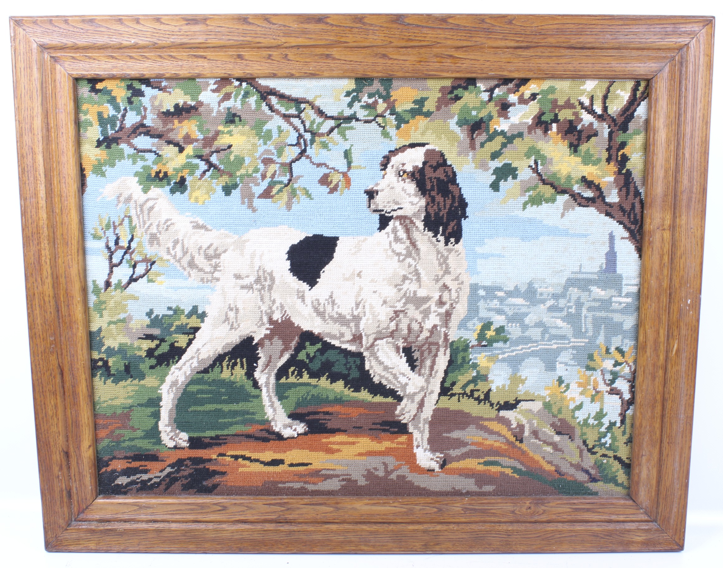 A framed needlepoint panel depicting a hunting dog.