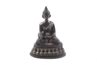 A Tibetan bronze figure of Buddha Shakyamuni with white metal inlay.