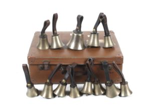 A vintage faux leather case containing thirteen hand bells and documents. With leather loop handles.