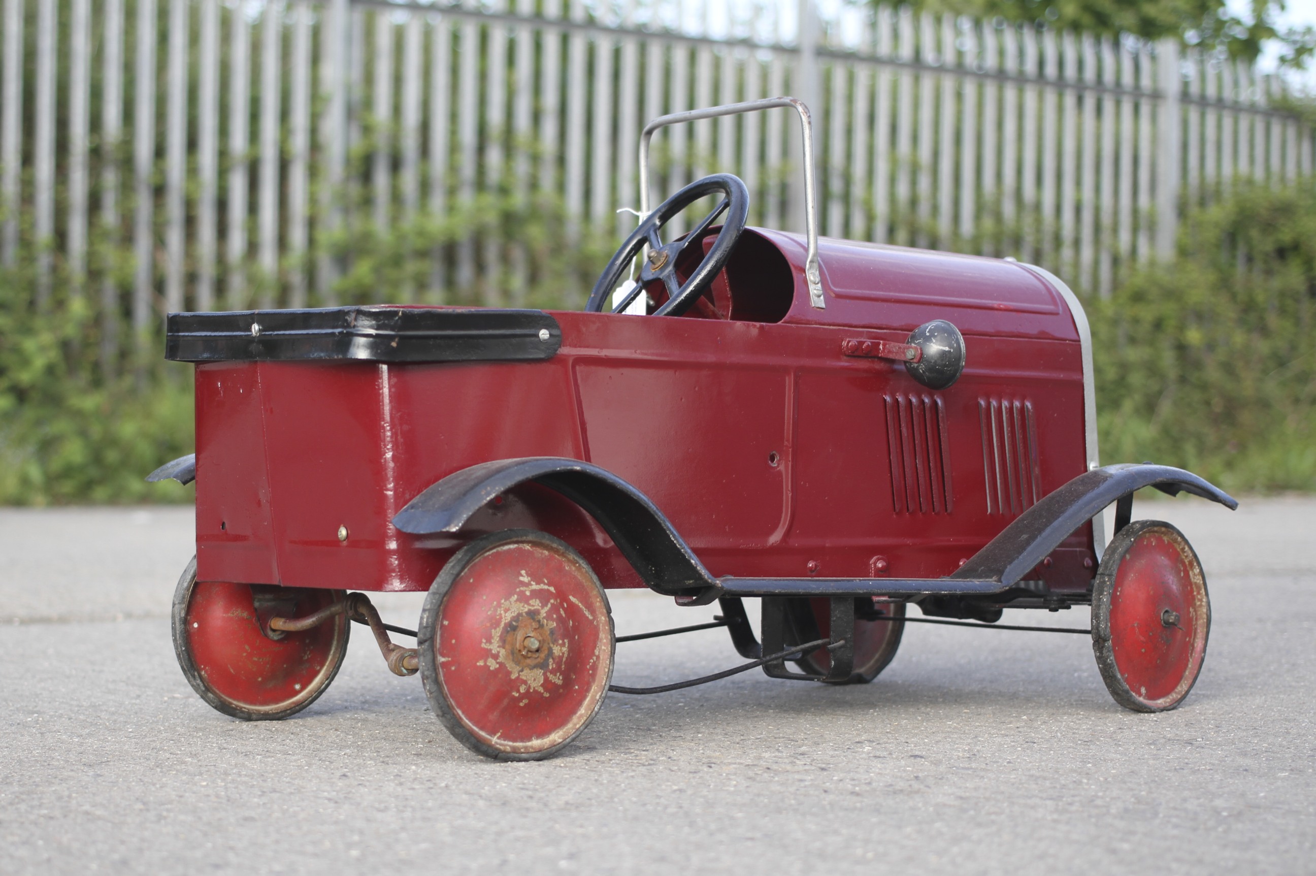 A circa 1930s tin plate pedal car. Red body with black trim and red wheels, H49cm x L77cm. - Image 2 of 3