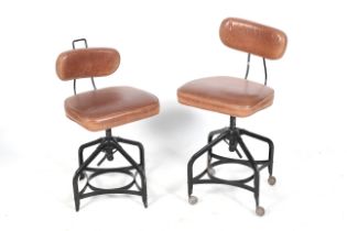 Two industrial style adjustable leather and metal office chairs.