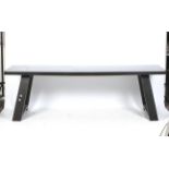 A large contemporary wooden dining table. Painted black, with angled supports, H75cm x W240cm x D70.