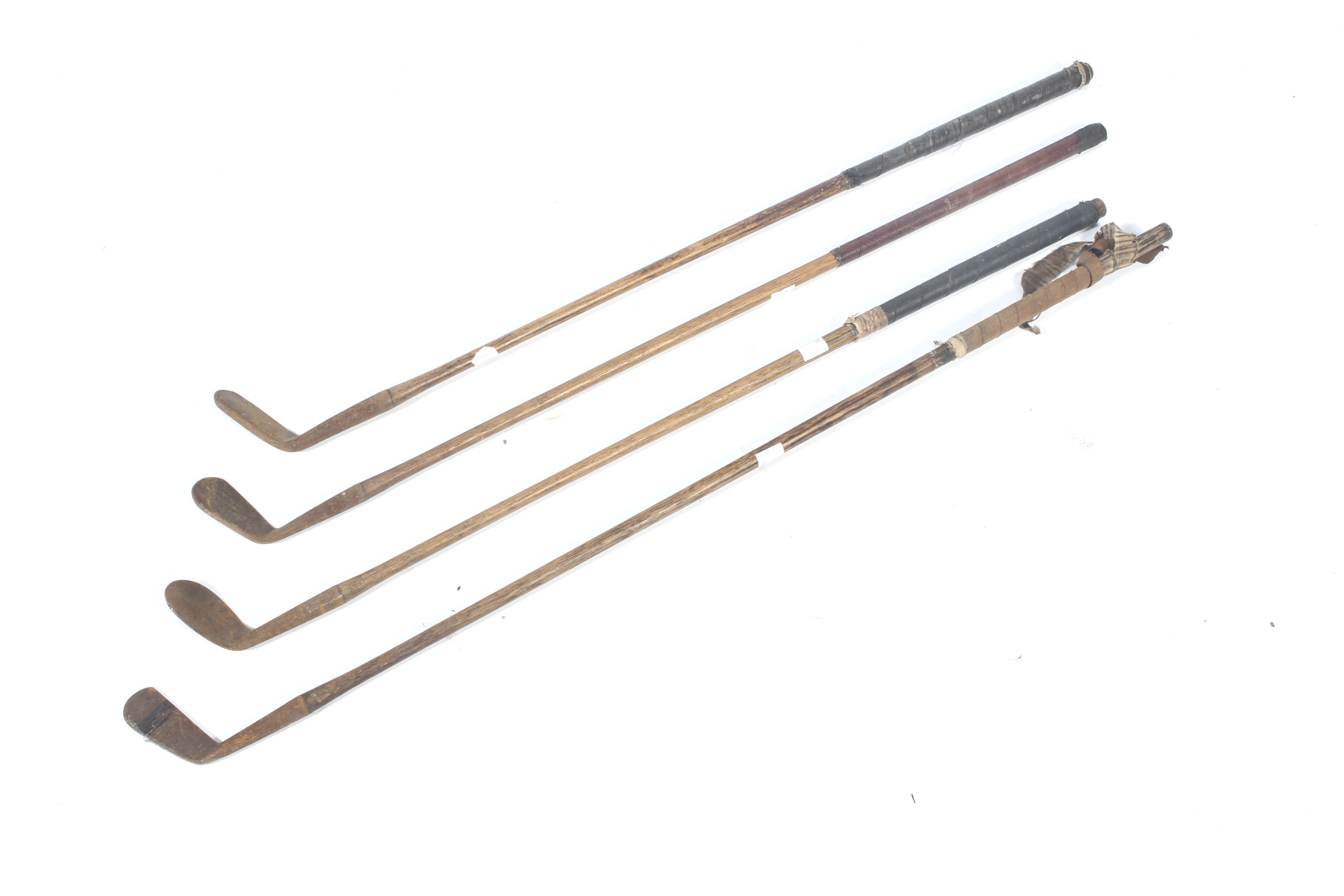 A collection of four Hickory golf clubs.