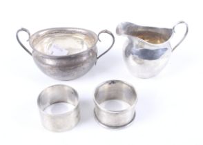 A late Victorian silver oval cream jug and a matching sugar bowl and two napkin rings.