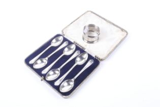 A silver napkin ring and a set of six silver tea spoons with crossed golf club terminals.