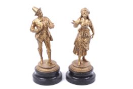 A pair of gilt spelter figures. Modelled as apple pickers, mounted on circular wooden bases.