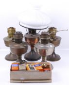 A collection of five oil lamps, a white shade and accessories.