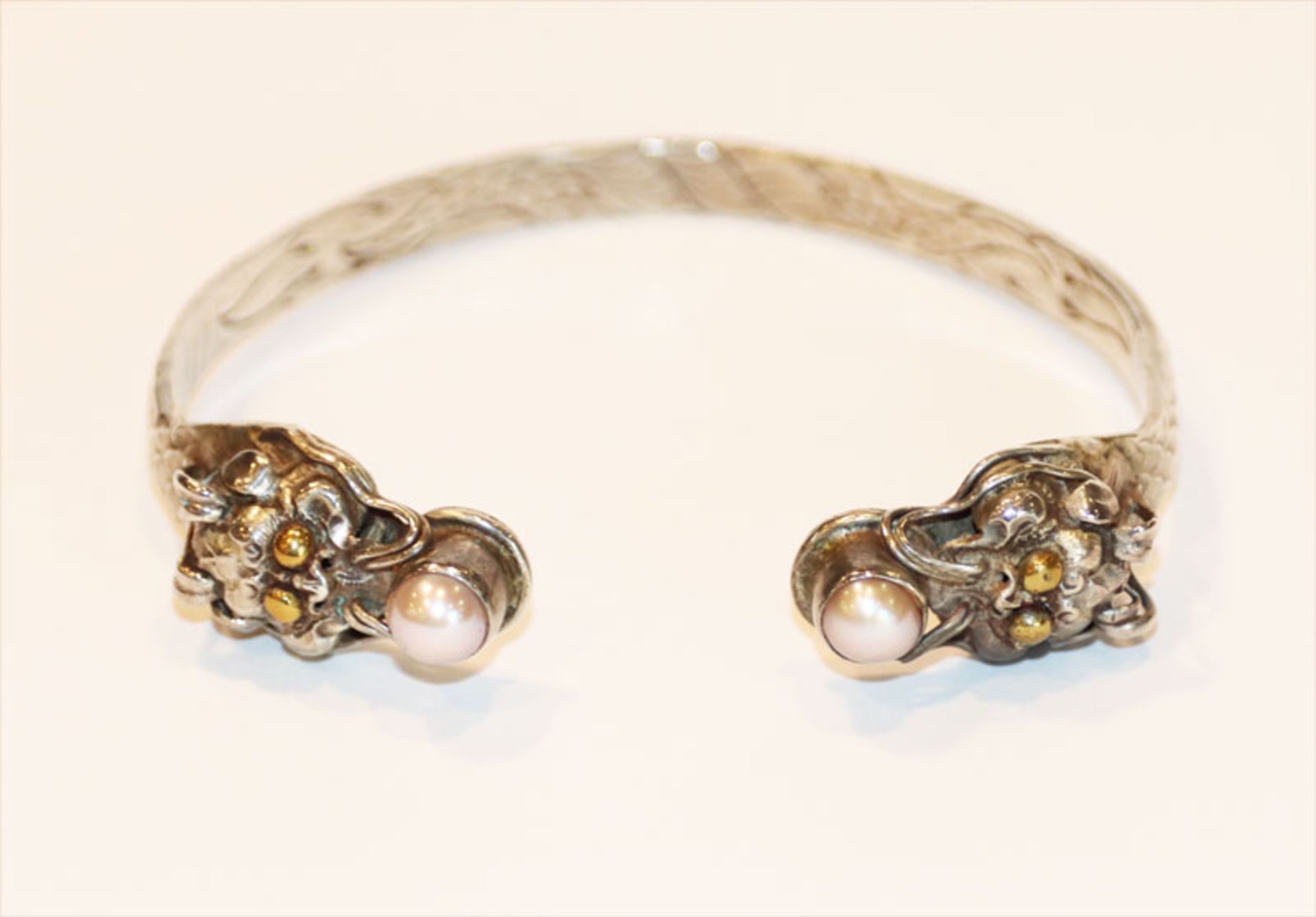 Silber Armspange mit Schuppenrelief und Tierköpfen, besetzt mit je einer Perle, D 6 cm, 23 gr.,