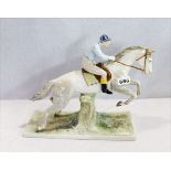 Porzellanskulptur 'Pferd mit Jockey auf naturalistischem Sockel', farbig glasiert, an der Seite