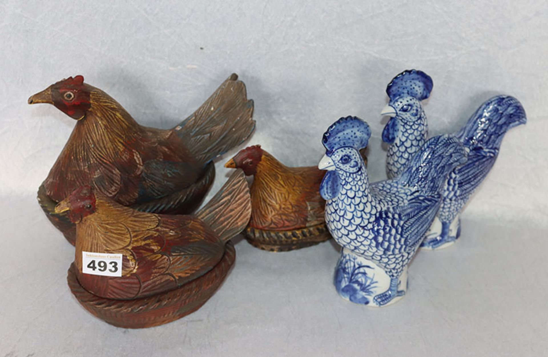 3 Holzdosen in Form von Hühnern, bemalt, H 13/20 cm, und 2 Porzellanfiguren 'Hühner', blau bmalt,